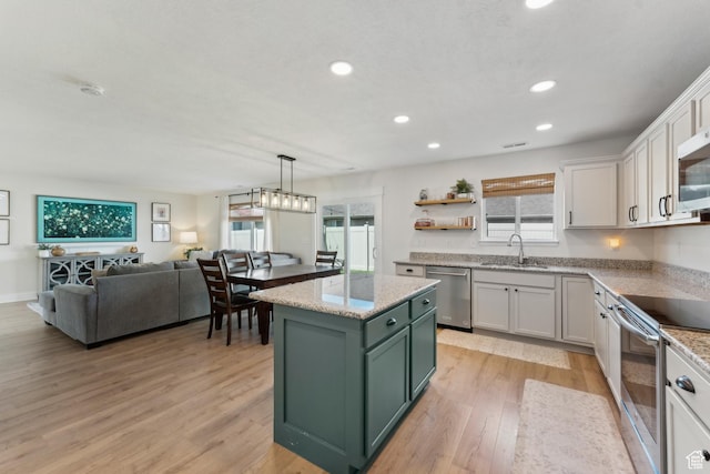 kitchen with a sink, white cabinetry, stainless steel appliances, green cabinets, and light wood-style flooring