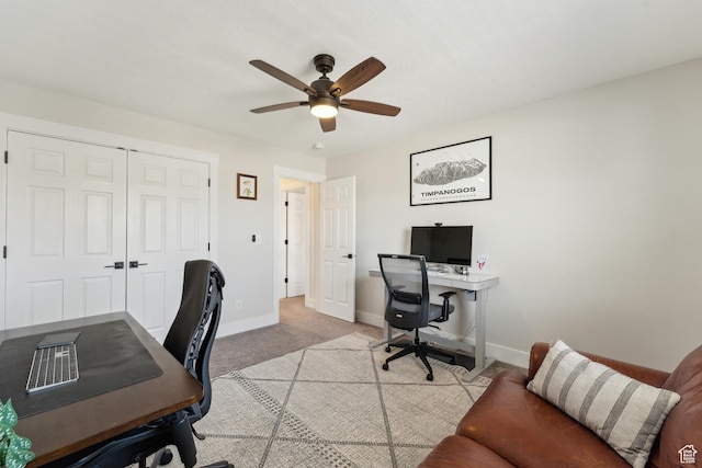 home office featuring light carpet, baseboards, and ceiling fan