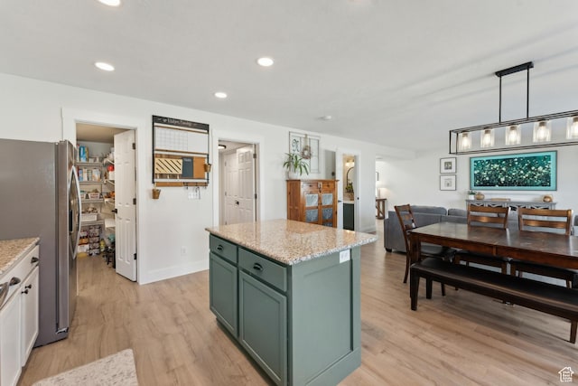 kitchen with light wood-style floors, green cabinets, stainless steel refrigerator with ice dispenser, a center island, and light stone counters