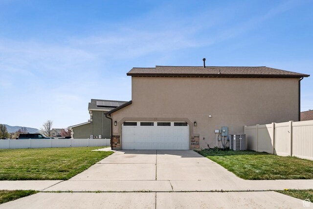 view of side of property with central AC, a lawn, fence, concrete driveway, and stucco siding