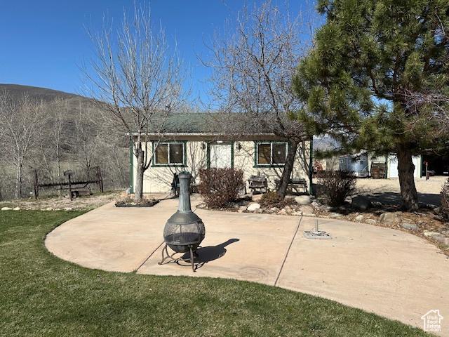 back of property with a yard, a fire pit, and a patio