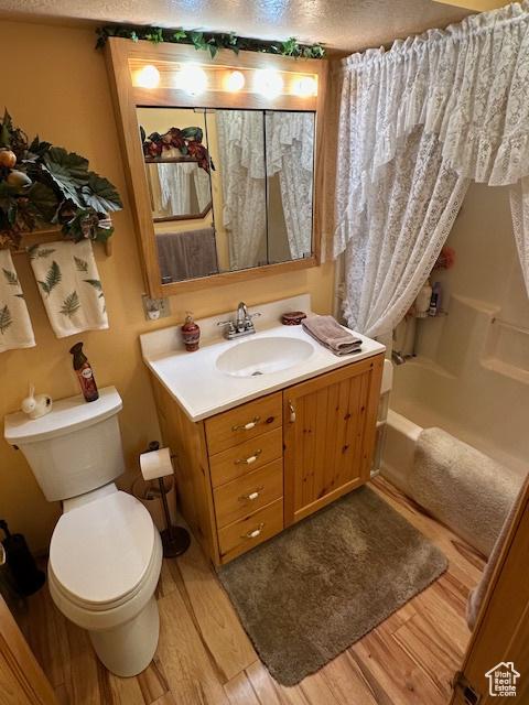 bathroom featuring toilet, a textured ceiling, wood finished floors, and vanity