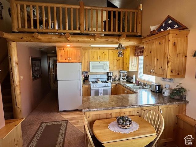 kitchen featuring white appliances, a high ceiling, a sink, and a peninsula