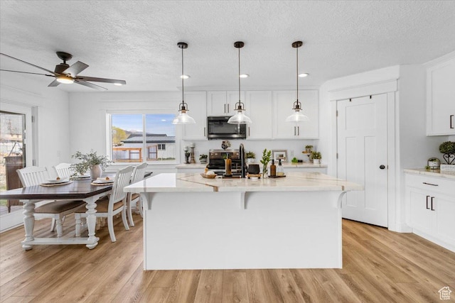 140 S 100 E, Wales, UT 84667 - kitchen featuring stainless steel appliances, an island with sink, light wood-style floors, and white cabinetry