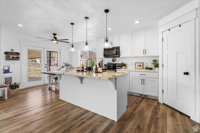 140 S 100 E, Wales, UT 84667 - kitchen featuring white cabinets, light countertops, a kitchen island with sink, a kitchen bar, and stainless steel appliances
