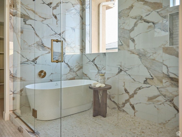 bathroom featuring a marble finish shower, tile patterned floors, and a freestanding bath