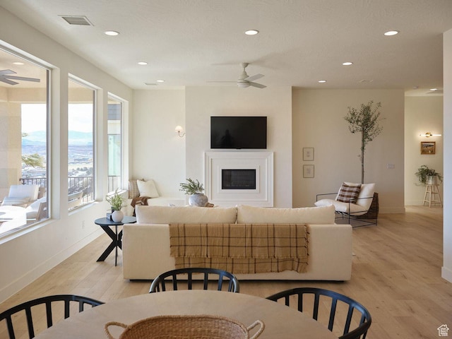 living room with recessed lighting, visible vents, light wood-type flooring, and a ceiling fan