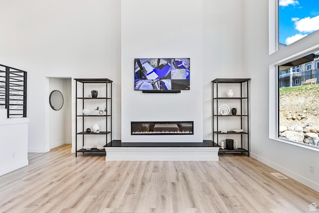 94 S 950 E, Hyde Park, UT 84318 - unfurnished living room with wood finished floors, a glass covered fireplace, and a towering ceiling