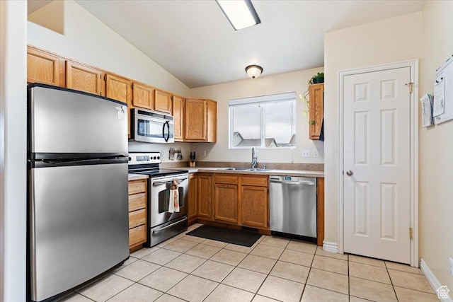 kitchen featuring a sink, light countertops, appliances with stainless steel finishes, vaulted ceiling, and light tile patterned flooring