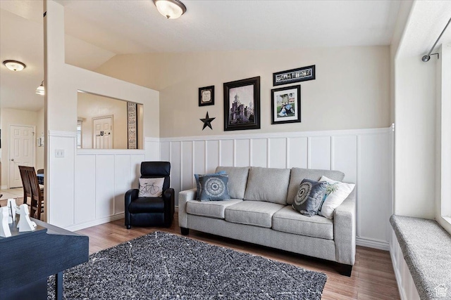 living area featuring wood finished floors, wainscoting, and vaulted ceiling
