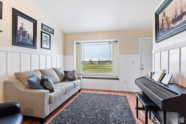living room with wood finished floors, wainscoting, and visible vents