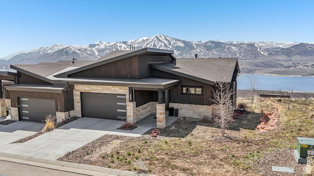 view of front of home with a mountain view, stone siding, driveway, and roof with shingles