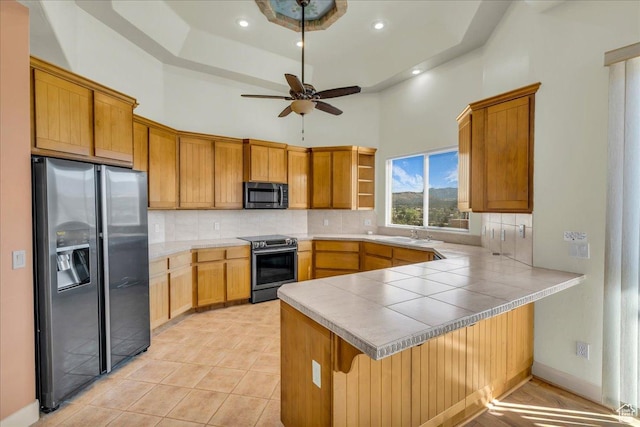 kitchen with ceiling fan, a peninsula, a high ceiling, stainless steel appliances, and backsplash