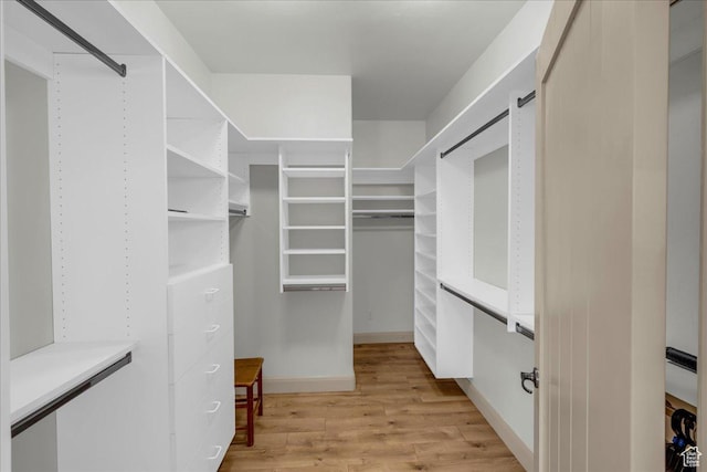walk in closet with light wood-style floors