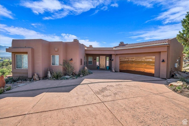 adobe home featuring a tile roof, a garage, and concrete driveway