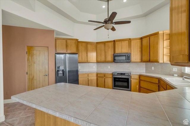 kitchen with appliances with stainless steel finishes, ceiling fan, a sink, and backsplash