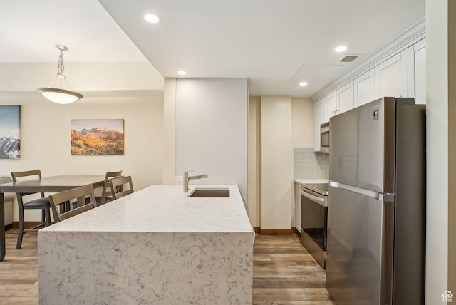 3720 N Sundial Ct Unit Cg02, Park City, UT 84098 - kitchen featuring white cabinets, a sink, appliances with stainless steel finishes, light wood finished floors, and decorative backsplash