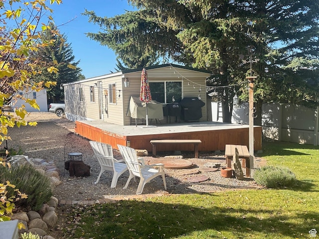 rear view of property featuring a yard, a wooden deck, and fence