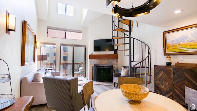 living room featuring a fireplace, stairway, a high ceiling, and wood finished floors