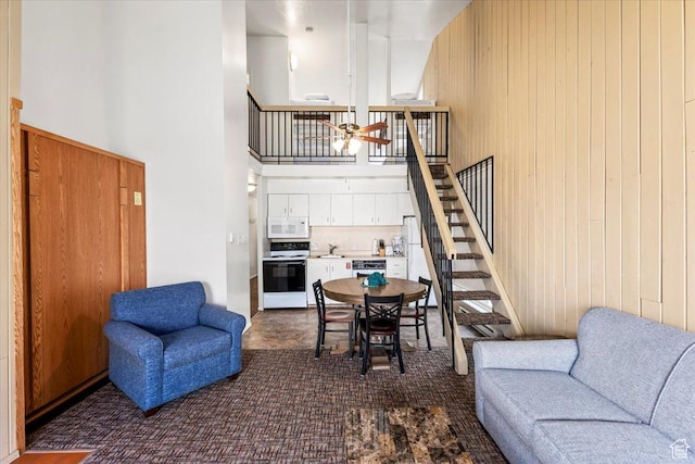 2176 S Bear Blvd, Garden City, UT 84028 - living room featuring wood walls, stairway, a high ceiling, and ceiling fan