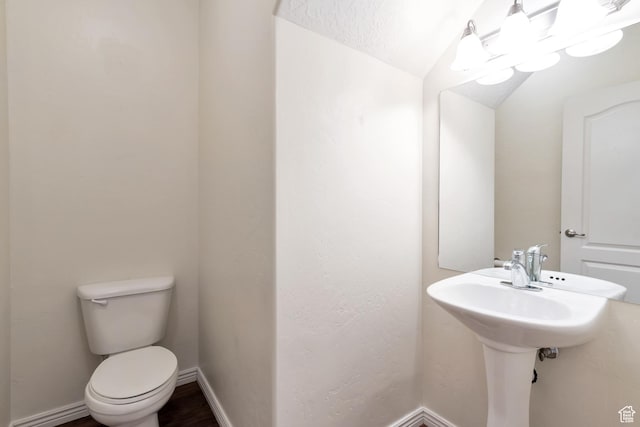 bathroom with baseboards, vaulted ceiling, toilet, and wood finished floors