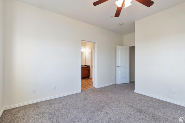 unfurnished bedroom with light carpet, ensuite bathroom, baseboards, and a ceiling fan