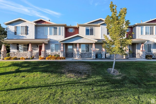 view of front of home with a front yard, stone siding, and covered porch