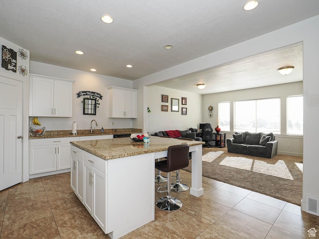 8092 W Rock Creek Cove Ln, Eagle Mountain, UT 84005 - kitchen featuring light tile patterned floors, a center island, white cabinets, open floor plan, and a kitchen breakfast bar