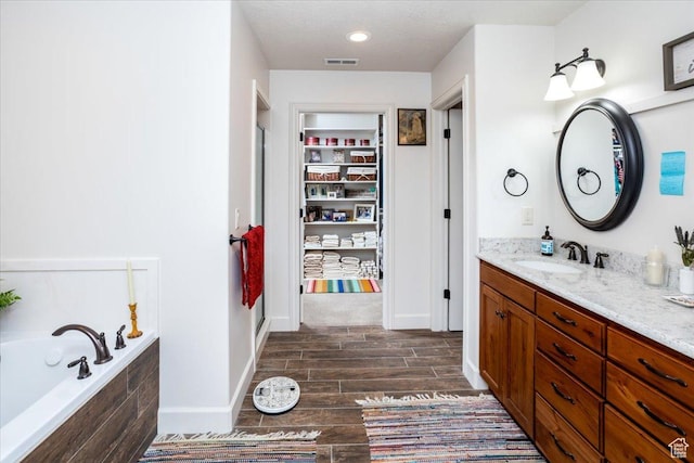 1510 S Mahogany Dr, Garden City, UT 84028 - bathroom featuring visible vents, a garden tub, vanity, and wood finish floors