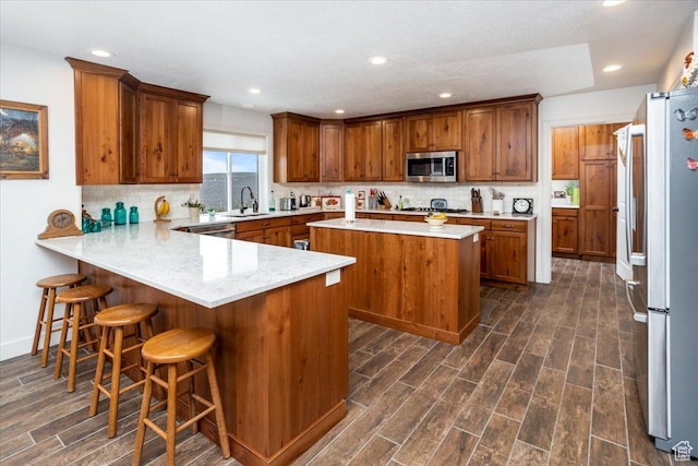 1510 S Mahogany Dr, Garden City, UT 84028 - kitchen with a sink, dark wood-style flooring, a peninsula, brown cabinetry, and stainless steel appliances