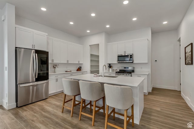 1919 S Sawmill Blvd E, Heber City, UT 84032 - kitchen with light wood-type flooring, light countertops, a kitchen island with sink, appliances with stainless steel finishes, and a sink