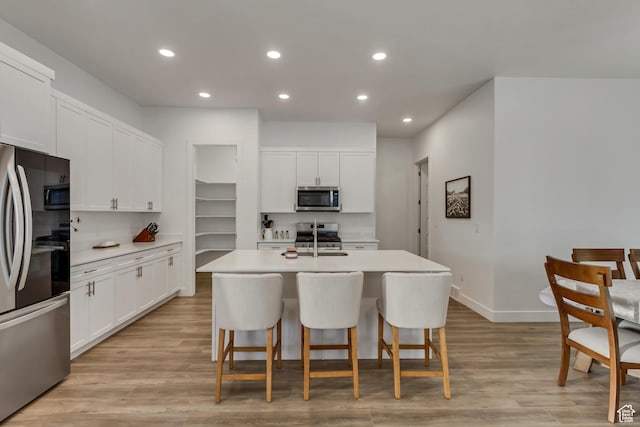 1919 S Sawmill Blvd E, Heber City, UT 84032 - kitchen with an island with sink, a kitchen breakfast bar, white cabinetry, recessed lighting, and stainless steel appliances