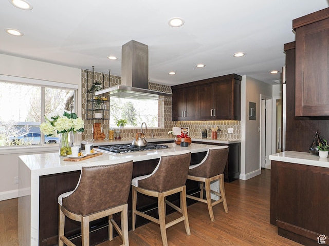 2463 E Michigan Ave S, Salt Lake City, UT 84108 - kitchen featuring island range hood, gas cooktop, backsplash, light countertops, and a kitchen bar