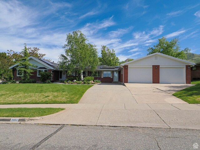 2463 E Michigan Ave S, Salt Lake City, UT 84108 - ranch-style home featuring a front lawn, driveway, roof mounted solar panels, brick siding, and a garage