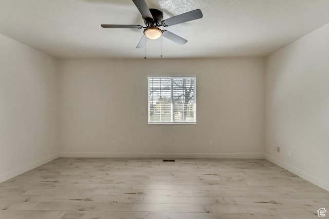 spare room with light wood finished floors, baseboards, and a ceiling fan