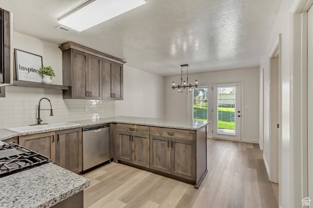 kitchen featuring visible vents, a sink, a peninsula, a textured ceiling, and stainless steel dishwasher