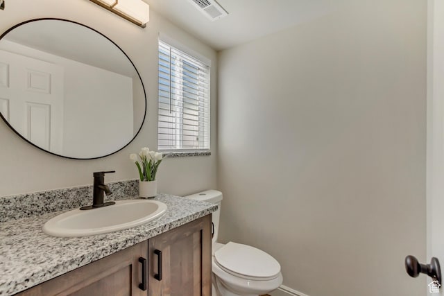 bathroom featuring toilet, vanity, and visible vents