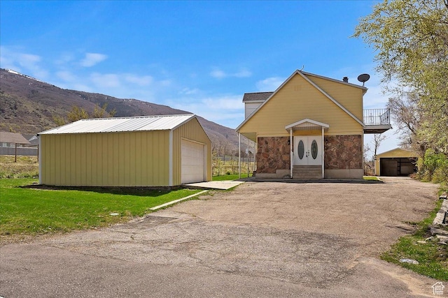 1202 E Mutton Hollow Rd, Kaysville, UT 84037 - view of front of house with a mountain view, stone siding, a garage, an outdoor structure, and a balcony