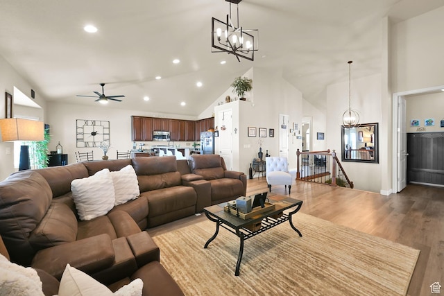 living area with light wood-style flooring, high vaulted ceiling, recessed lighting, and ceiling fan with notable chandelier