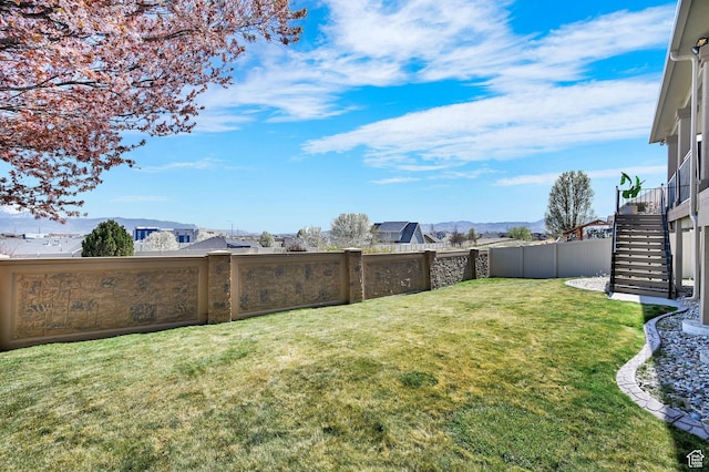view of yard with stairway, a fenced backyard, and a mountain view