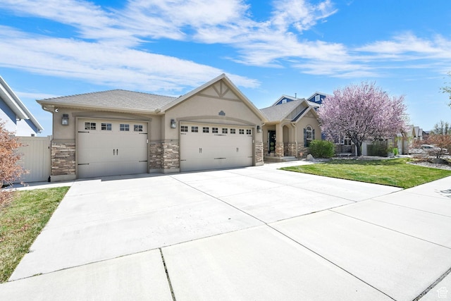 ranch-style house featuring stucco siding, a front yard, stone siding, an attached garage, and concrete driveway