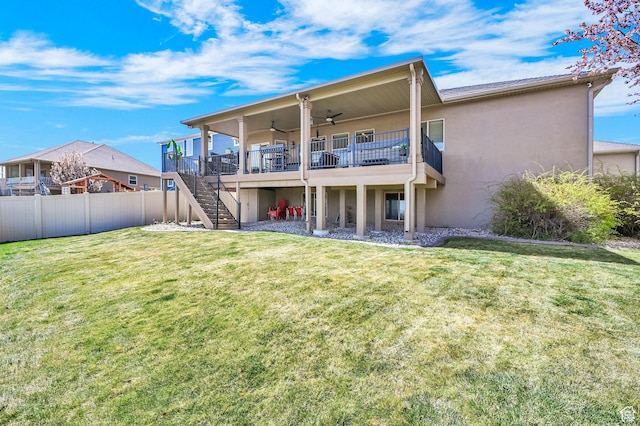 back of property with a yard, a ceiling fan, stairway, and stucco siding