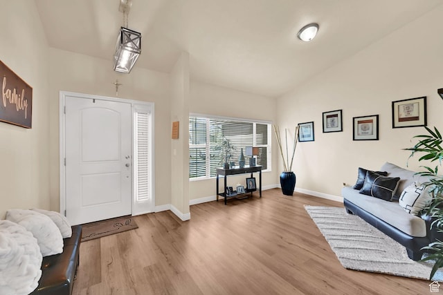 entryway featuring light wood-style flooring, vaulted ceiling, and baseboards