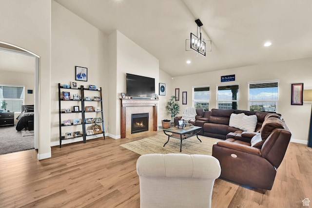 living area with a tile fireplace, baseboards, recessed lighting, high vaulted ceiling, and light wood finished floors