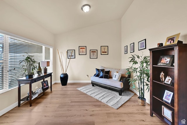 sitting room with baseboards, high vaulted ceiling, and wood finished floors