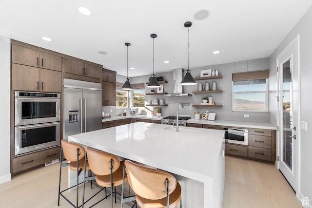 1026 W Chokecherry Dr Unit 135, Mapleton, UT 84664 - kitchen with appliances with stainless steel finishes, wall chimney exhaust hood, open shelves, backsplash, and light wood-style floors