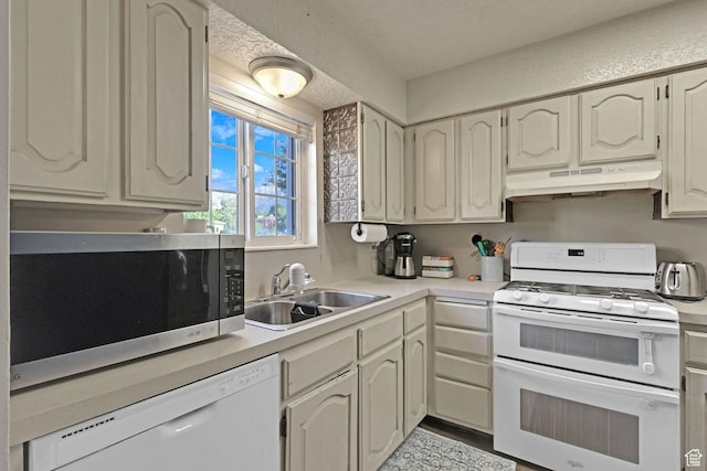 kitchen with light countertops, under cabinet range hood, a sink, and white appliances