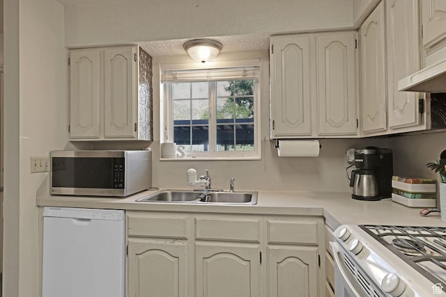 kitchen featuring light countertops, under cabinet range hood, a sink, and white appliances