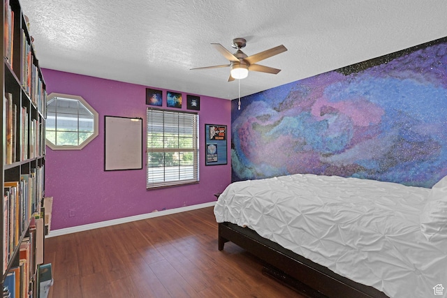 bedroom featuring baseboards, a ceiling fan, wood finished floors, and a textured ceiling