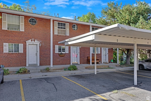 view of front of home with covered and uncovered parking and brick siding